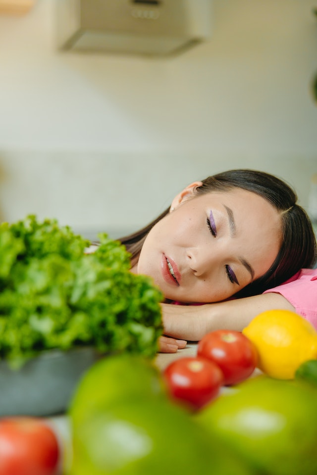 A woman is sleeping by fruits and vegetables