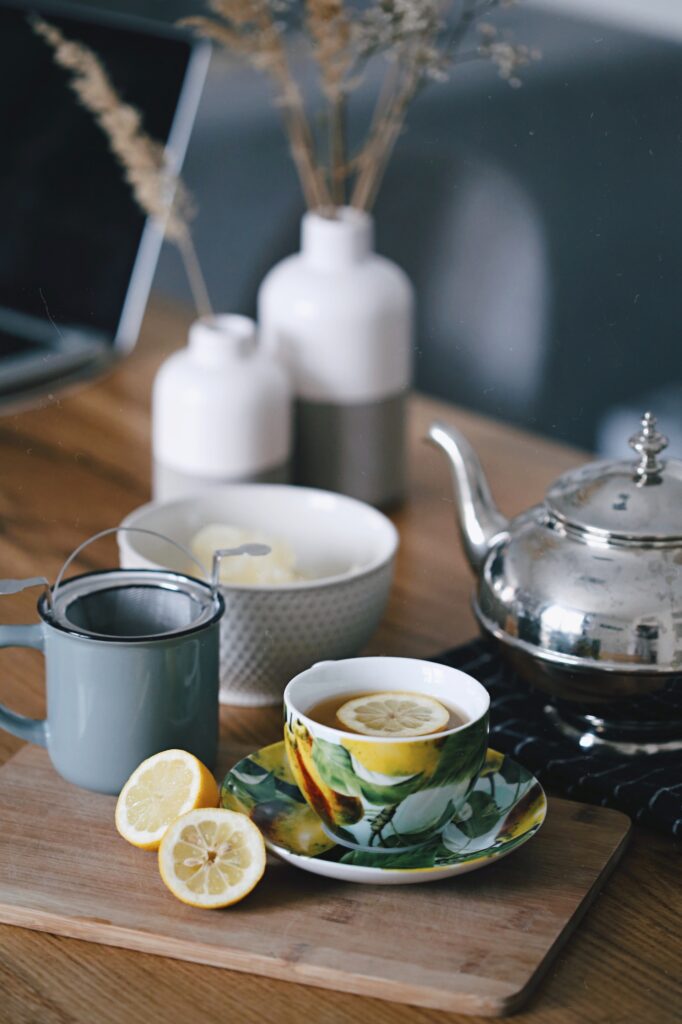 Gray teapot beside a mug filled with tea and lemon, representing hydration for a productive day ahead