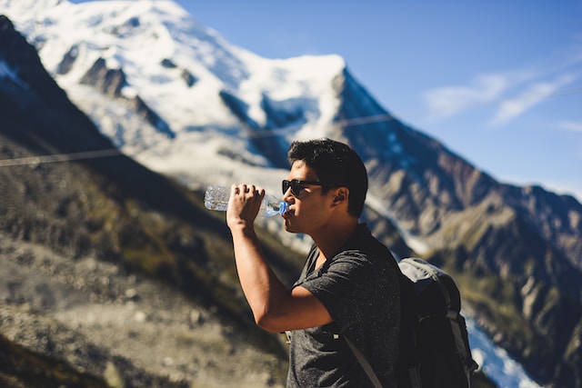 A man drinking water on the mountain- to stay hydrate