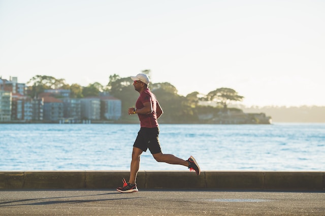 A man running near sea during daytime to improve his health and wellness