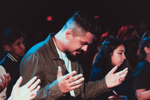 
A man praying in a group, seeking God's amazing grace