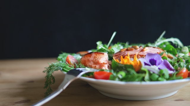 serving of salad and fish on white plate for health and wellness