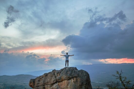 Man standing on top of rock mountain during the golden hour