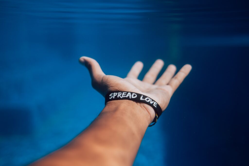  An outstretched hand with a "Spread Love" wristband, symbolizing God's children sharing grace.