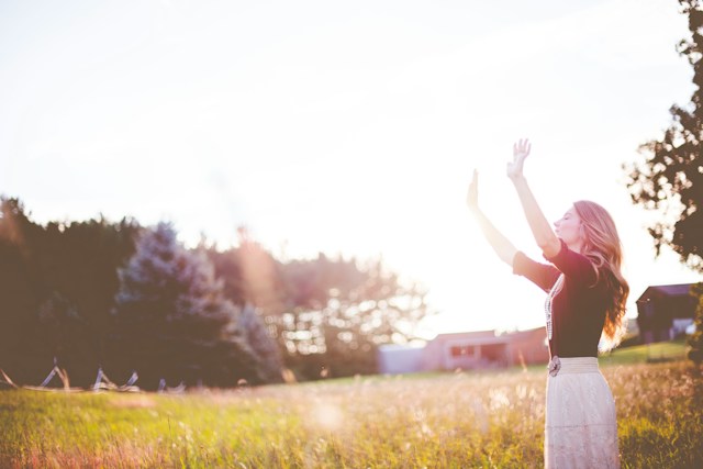 The Lord's Prayer-Woman hands up in front of green meadows