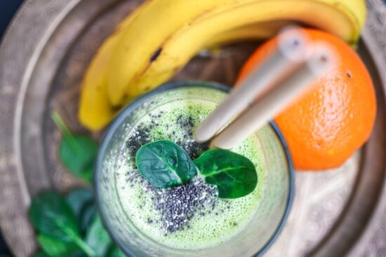 a glass of green smoothie with bananas & oranges