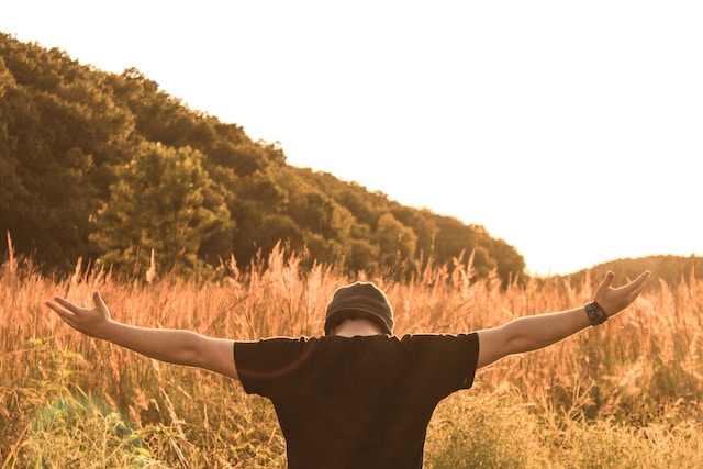 A man standing in the middle field-praying for well-being in the new year