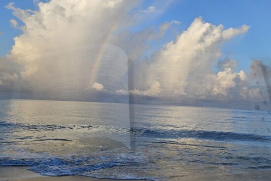 Image of a transparent Bible placed over a serene ocean scene with a rainbow and beautiful clouds, symbolizing Jesus the Son of God saving humanity