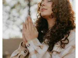 Woman praying with folded hands, representing the journey of Following Jesus for Beginners.